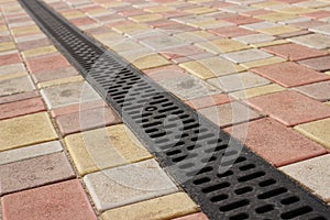 Rainwater drainage system on a sidewalk of colored tiles diagonal photo