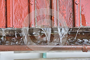 Rainwater flowing down from a damaged metal roof into the gutter during a downpour.