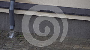 Rainwater flows down from the roof of the building through a drainpipe. Downpipe and splashes from the rain close-up. Heavy rain