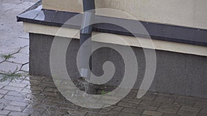 Rainwater flows down from the roof of the building through a drainpipe. Downpipe and splashes from the rain close-up. Heavy rain