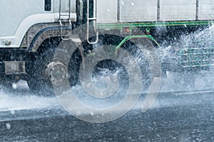 Rainwater spraying from motion truck wheels. city road during he