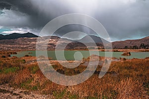 Rainy clouds over a green lagoon.