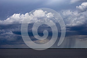 Rainy clouds over the river. Dark cloud in rainy weather over the river. Storm clouds over horizon. Stormy sky over the river.