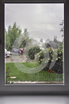 Rainy day view from the window, raindrops on glass, blurred cloudy rainy sky background