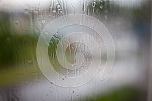 Rainy day through the window on sky and city buildings background