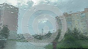 Rainy day through the windshield of a car on the background of city