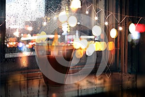 Rainy evening city view,car traffic light, from window people walk  , candle light reflection rain drops on glass urban