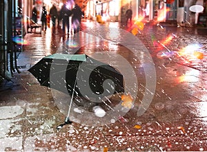 Rainy evening street in town ,Autumn leaves fall  ,rain drops ,people walking in neon vitrines light ,light blurred ,black umbrell