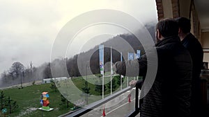 Rainy and foggy landscape with trees and fog all over the forested hills and the yard in front of hotel with green lawn