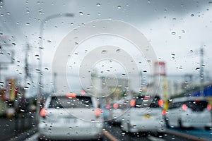 Rainy and gloomy day on the road with cars and traffic and rain is focused on the car`s windshield.