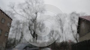 Rainy gloomy weather viewed from inside of a car with wipers actively removing rain drops from the windshield