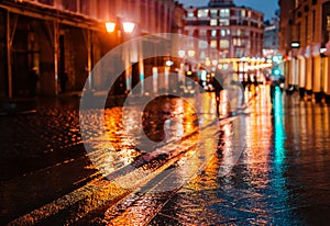 Rainy night in a big city, reflections of lights on the wet road surface.