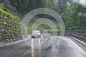 Rainy road surface and raindrops on a car windshield