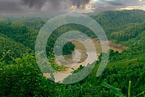 During the rainy season, the thick green hills blend into the thick black clouds in the sky. Sangu river flows below. Hilly region