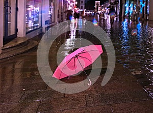 Rainy street pink umbrella in old town of tallinn blurring bokeh city light people walking under rainy sky