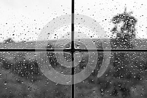 Rainy weather behind wet glass of a house window