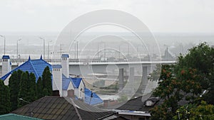 rainy weather. the movement of cars on the road bridge over the river. rooftops.