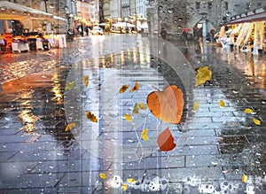 Rainy weather season Autumn leaves   rain in medieval  Tallinn old town   city wet pavement houses pedestrian people walk with umb