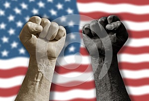 Raised black and white clenched fist in front of blurred waving American flag.