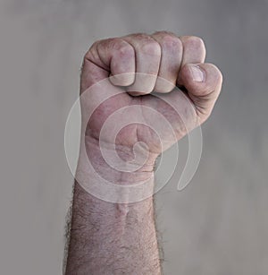 Raised clenched fist of adult male in the air as a threat of fighting. Stock photo with socialism, communism, revolution, workman