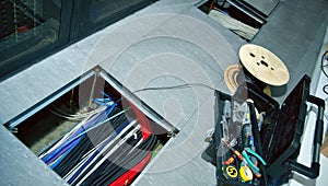 Raised floor (removable floor) in the server room with an open hatch on to the hatch are network cables.