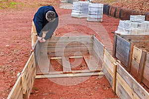 A raised garden bed is being built by men using wooden frame.