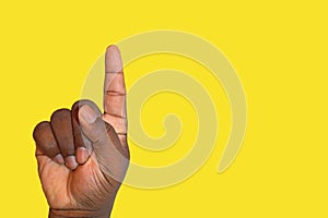 Raised hand asking for permission or answering a question on a yellow background - African ethnicity