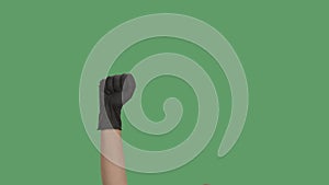 Raised hand in black gloves with clenched fist for protest on green screen chroma key background. Cropped shot of