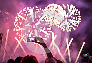 Raised hand with shooting horizontal night fireworks sky video smartphone . Colorful bright background entertainment with light