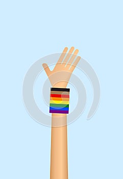 Raised hand wearing gay pride rainbow flag wristband on blue background