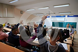 Raised hands and arms of large group of people in class room