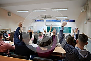 Raised hands and arms of large group of people in class room