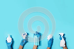 Raised hands in medical gloves holding masks, sanitizers, soap, non contact thermometer on blue background. Banner. Copy space.