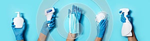 Raised hands in medical gloves holding masks, sanitizers, soap, non contact thermometer on blue background. Banner. Copy space.