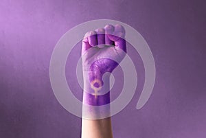 Raised purple fist of a woman for international women`s day and the feminist movement. March 8 for feminism, freedom