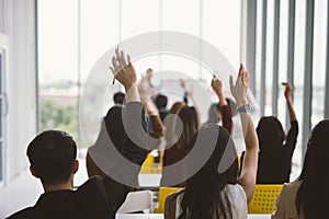 Raised up hands and arms of large group in seminar class room at Conference.