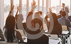 Raised up hands and arms of large group in seminar class room to agree with speaker at conference seminar meeting room.