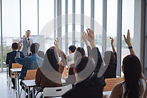 Raised up hands and arms of large group in seminar class room to agree with speaker at conference seminar meeting room.