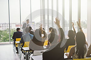 Raised up hands and arms of large group in seminar class room to agree with speaker at conference seminar meeting room.