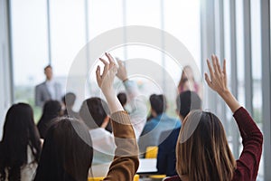 Raised up hands and arms of large group in seminar class room to agree with speaker at conference seminar meeting room.