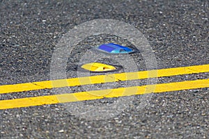 Raised yellow pavement marker separates opposing traffic lanes. The blue marker denotes a fire hydrant location