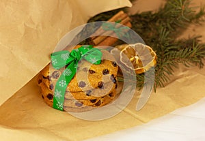 Raisin cookies with christmas ribbon, lemon, cinnamon and spruce branch on craft paper