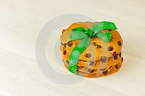 Raisin cookies tied with green christmas ribbon on white wooden table