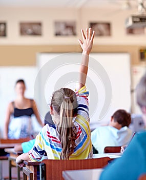 Raising her hand...A young school girl raising her hand to ask a question.