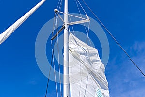 Raising the sail on a yacht. Young man captan lifting the sail of catamaran yacht during cruising