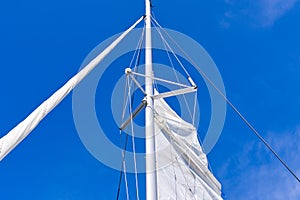 Raising the sail on a yacht. Young man captan lifting the sail of catamaran yacht during cruising