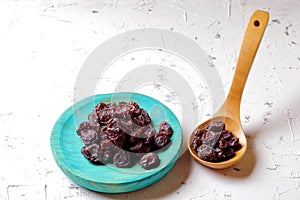 Raisins on aquamarine plate and brown wooden spoon