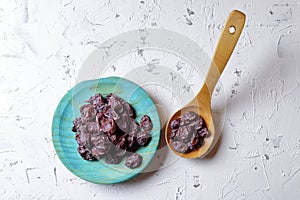 Raisins on aquamarine plate and brown wooden spoon photo