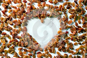 The raisins are located on a white surface in the shape of a heart.