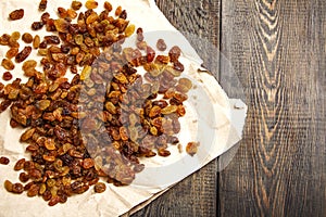 Raisins on parchment paper on a wooden table. View from above. Close-up.